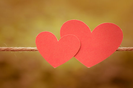 vintage two red paper hearts hearts hanging on the Natural background.