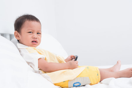 Cute boy asian baby playing a smartphone in the roomの写真素材