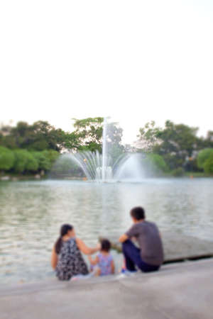 The family sat at the waterfront, fountain in the pool.の写真素材