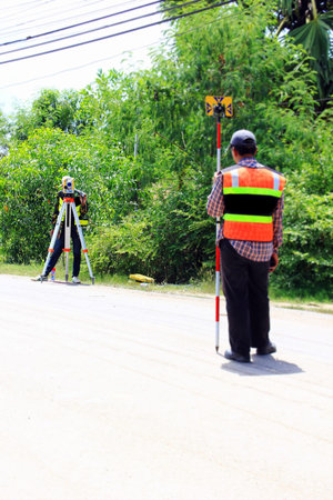 Two technicians are measuring the road level with theodolite.