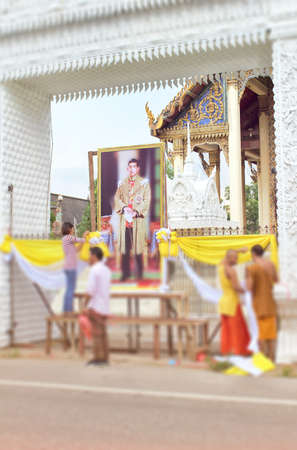 Photographs of the king of Thailand are decorated with cloth by the monks at the temple gate.のeditorial素材