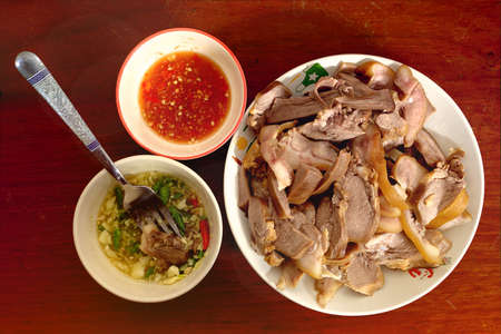 Boiled pork tongue with a cup of sauce on wooden floor.のeditorial素材