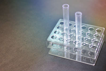 Empty plastic test tube Two tubes on the holder Black leather tabletop background.Glass test tube in science laboratory, black backgroundのeditorial素材