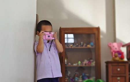 Kindergarten students in a school uniform holding a pink camera Toy cabinet backgroundのeditorial素材
