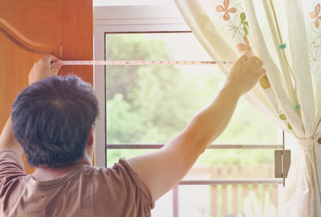 People are doing distance measurement Wide glass window frame Bright morning light The room has curtains. Brown doorのeditorial素材