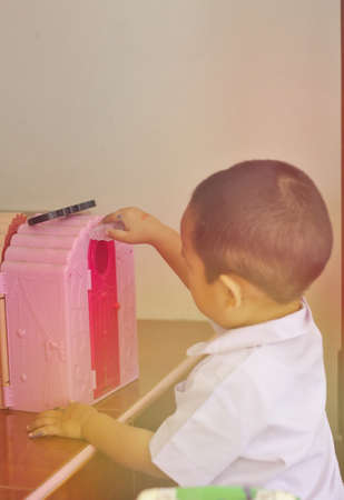 White kindergarten children with pink house toy box with morning sunshine Learning with toys in the classroom for young childrenのeditorial素材