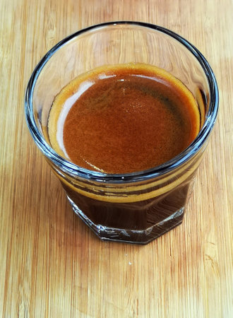 Close-up shot of a double shot of espresso in glass on wooden table.の写真素材
