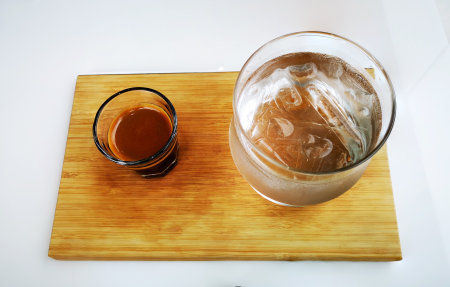 Isolated close-up shot of a double shot of espresso in glass, iced water on wooden tray, isolated object on the white background.の写真素材