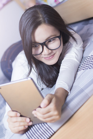 Woman using a tablet at bedroomの写真素材