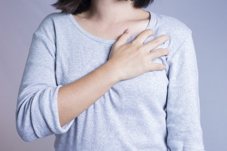 Woman having a pain in the heart area, isolated in white backgroundの写真素材