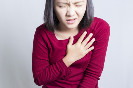 Woman having a pain in the heart area, isolated in white backgroundの写真素材