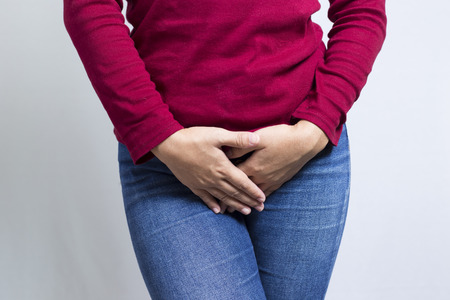 Woman with Hands Holding her Crotch Isolated in a White Backgroundの写真素材