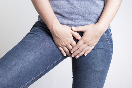 Woman with Hands Holding her Crotch Isolated in a White Backgroundの写真素材