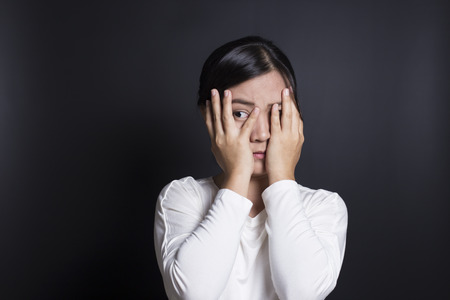 Woman hiding face laughing timidの写真素材