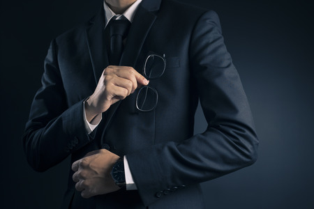 Businessman Pick Glasses: Isolated Black Backgroundの写真素材