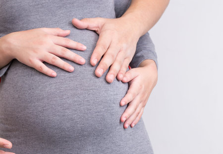 Pregnant woman and her husband holding her hands and touching her belly