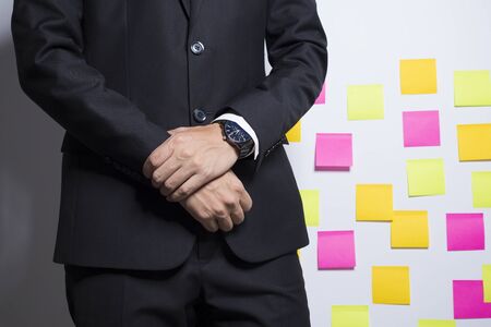 Businessman in black suit on notepaper backgroundの写真素材