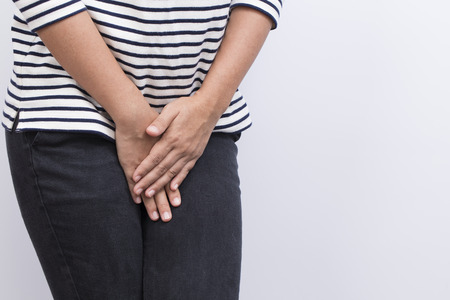 Woman with Hands Holding her Crotch Isolated in a White Backgroundの写真素材