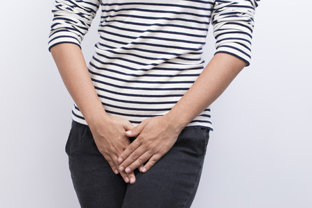 Woman with Hands Holding her Crotch Isolated in a White Backgroundの写真素材