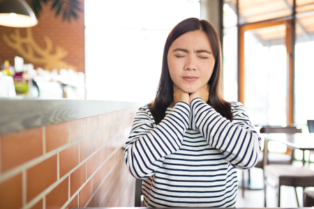 Woman has sore throat in the cafeの写真素材