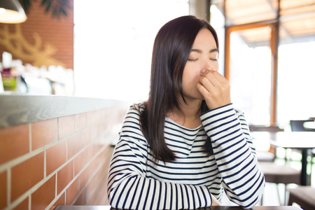 Woman has sneezing in cafeの写真素材