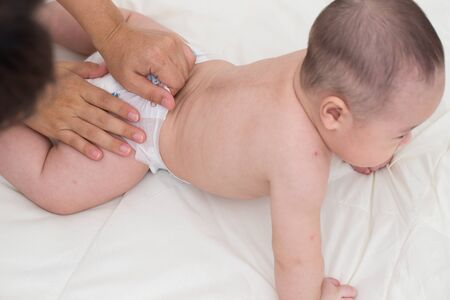 Mother changing a diaper to babyの写真素材