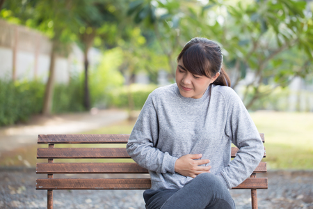 Woman has stomachache at parkの写真素材