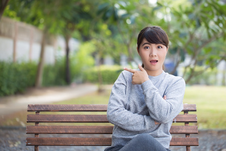 Happy woman at park pointing to copy spaceの写真素材