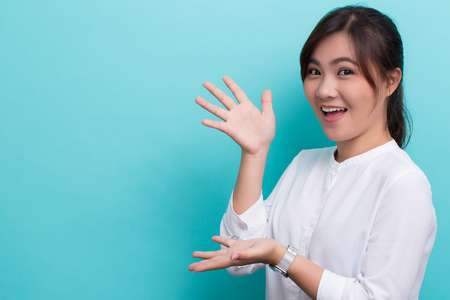 Asian woman show the copy space isolated on blue backgroundの写真素材