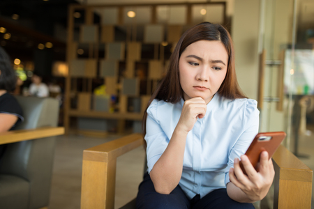Woman using smartphone in cafe and she feel worriedの写真素材