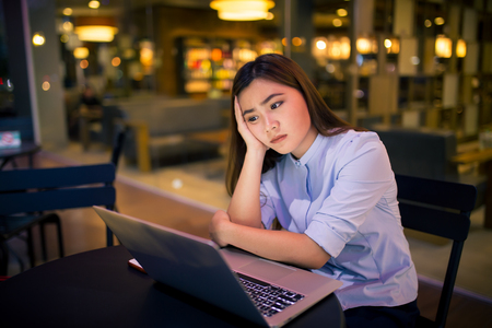Woman  using laptop in night time at cafe  she feel worriedの写真素材