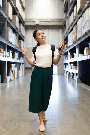 Woman shopping for furniture in warehouse and use smart phone for check priceの写真素材