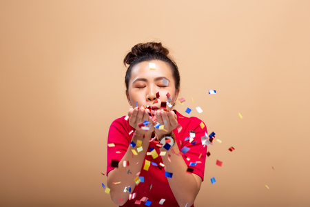 Portrait of a cheerful woman with confetti rain and celebrating isolated over backgroundの写真素材