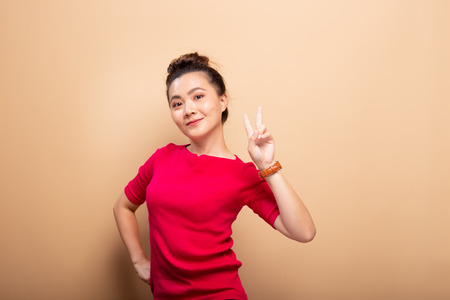 Portrait of happy woman smile and showing peace sign with fingers isolated over backgroundの写真素材