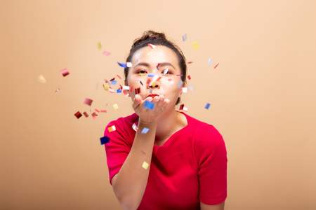 Portrait of a cheerful woman with confetti rain and celebrating isolated over backgroundの写真素材