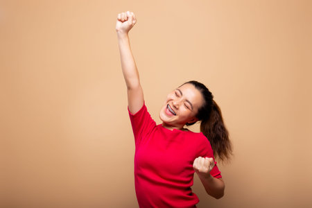 Happy woman make winning gesture isolated on backgroundの写真素材