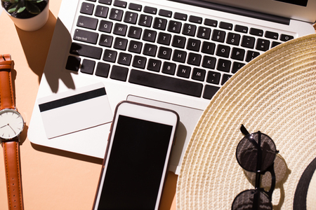 Laptop and smart phone with items for vacation time over isolatedの写真素材