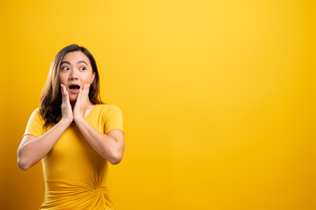 Portrait of excited woman isolated over yellow backgroundの写真素材