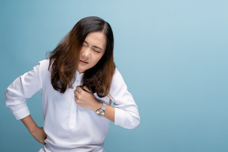 Woman has chest pain isolated over blue backgroundの写真素材