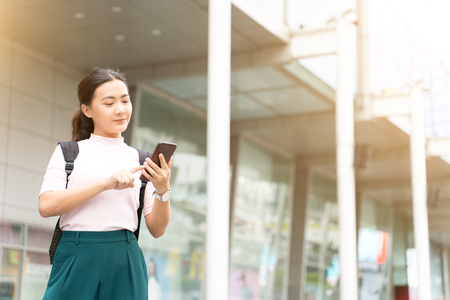 Happy woman using smart phone in the cityの写真素材