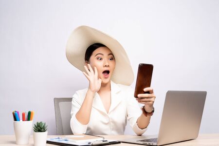 Woman wearing hat use smart phone taking a selfie at office isolated over backgroundの写真素材