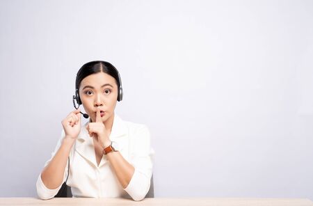 Woman operator in headset make whisper gesture over white backgroundの写真素材