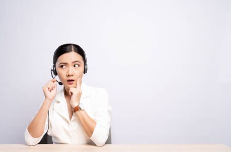 Woman operator in headset feel confuse over white backgroundの写真素材
