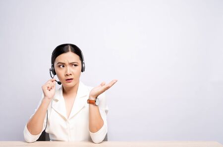 Woman operator in headset feel confuse over white backgroundの写真素材