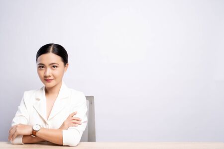 Portrait of a confident woman sitting isolated over backgroundの写真素材