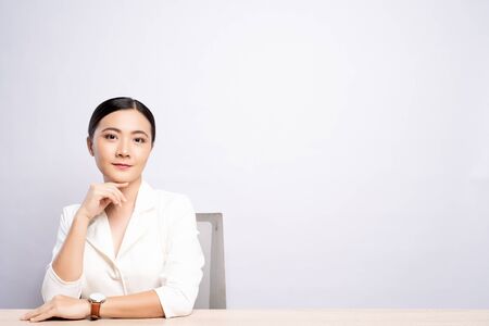 Portrait of a confident woman sitting isolated over backgroundの写真素材