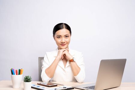 Portrait of a confidence woman sitting at office isolated over backgroundの写真素材