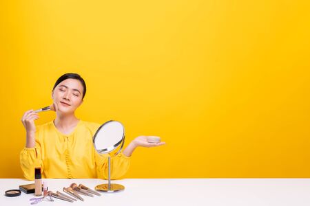 Woman making make-up near mirror and sitting at the deskの写真素材
