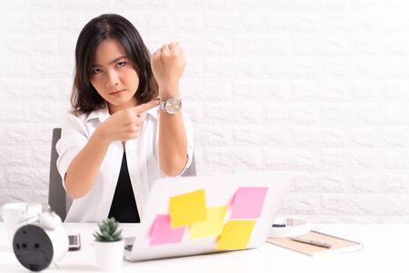 Angry woman pointing at her watchの写真素材