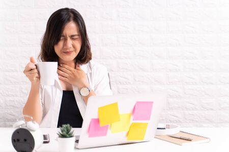 Sick woman at office with feverの写真素材